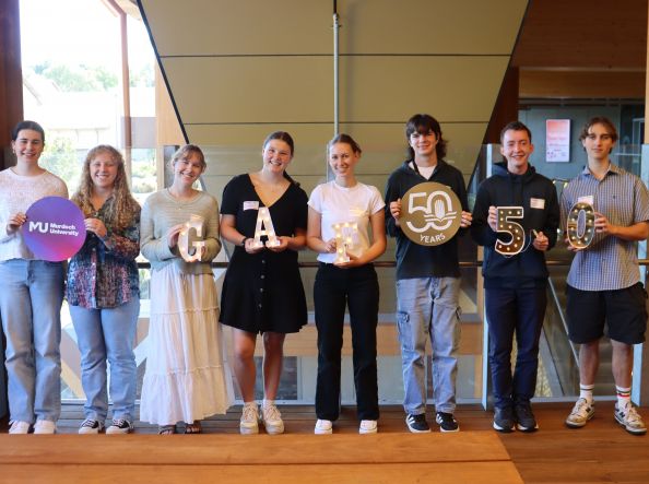 Murdoch GAF scholars lined up smiling while holding photo props that spell out GAF 50