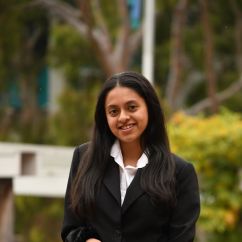 Young woman posing at photo in collared white shirt and black blazer.