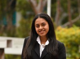 Young woman posing at photo in collared white shirt and black blazer.