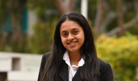 Young woman posing at photo in collared white shirt and black blazer.