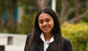 Young woman posing at photo in collared white shirt and black blazer.